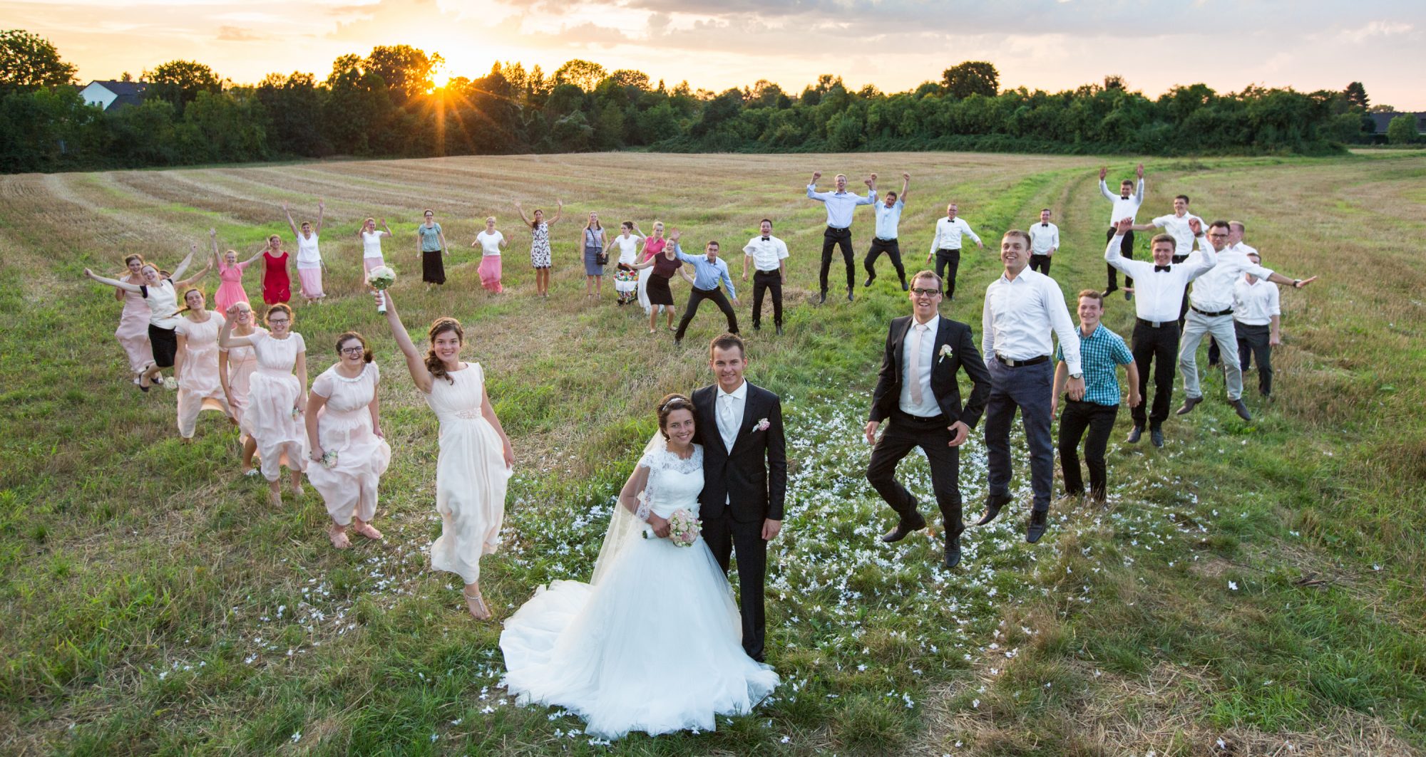 Freunde und Jugendliche auf dem Feld mit Hochzeitspaar